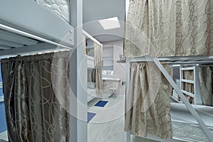 Hostel room. Empty bunk wooden beds with fabric curtains