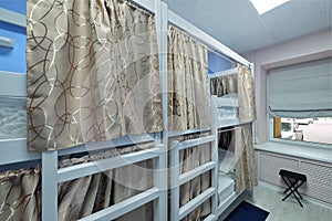 Hostel room. Empty bunk wooden beds with fabric curtains