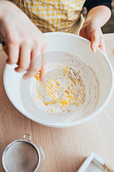 The hostess kneads the dough with a whisk in a white plastic bowl - baking homemade pies with jam