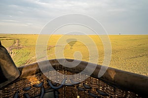 Hot air ballon ride - view of the balloon shadow over the Masaai Mara Reserve in Kenya. Basket point of view. Vast landscape