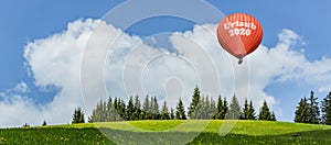 Hot air ballon `Urlaub 2020`  in landscape with forest