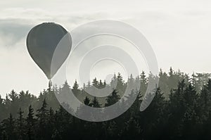 Hot air balloon above the foggy forest