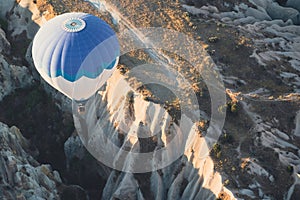 Hot air balloon with blue and white colors pattern rising over the Cappadocian valley