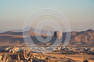 Hot air balloon with checkered pattern rising over the Cappadocian valley