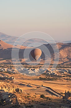Hot air balloon with checkered pattern rising over the Cappadocian valley