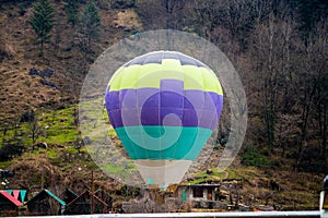 Hot air balloon with fire heating air in wicker basket with himalaya mountains in background showing this adventure in
