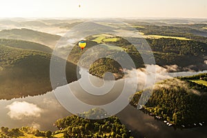 Hot air balloon floating in the morning light over Slapy dam