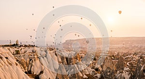 Hot air balloon flying over Cappadocia mountain landscape at gold sunrise