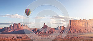 Hot Air Balloon flying over Desert Rocky Mountain American Landscape.