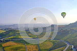 Hot air balloon flying over Langhe vineyards, fall season. Color image.