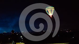 Hot air balloon flying over spectacular Cappadocia under the sky with milky way and shininng star at night with grain