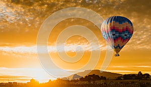 Hot air balloon flying at yellow sunrise