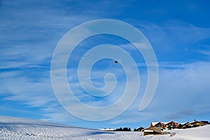 Hot-air balloon high above farm houses in snow covered landscape of Bavaria, Germany