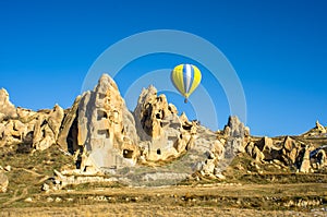 Hot air balloon overhanging the ancient dwellings of Cappadocia, Turkey