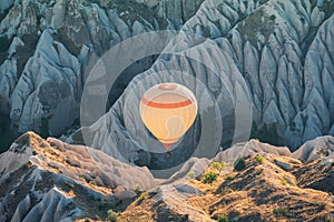 Hot air balloon rising over the Cappadocian valley with chimney houses in the background