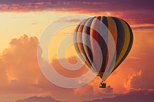 A hot air balloon rising under partly cloudy skies during a brillant sunset