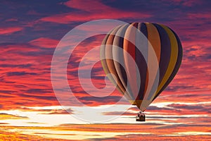 A hot air balloon rising under partly cloudy skies during a brillant sunset photo