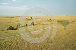 Hot air balloon shadow on the plains of the Masaai Mara in Kenya Africa. Dirt roads and zebras in distance