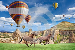 Hot air ballooning and two horses running in Cappadocia, Turkey. photo