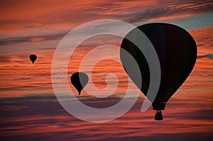 Hot-air balloons floating among clouds at dawn