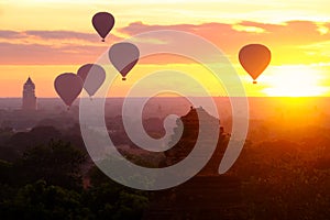 Hot air balloons fly over the ancient pagodas of old Bagan in Myanmar at sunrise.