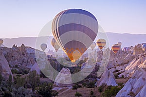 Hot air balloons flying in beautiful Cappadocia hilly landscape, amazing tourism attraction in Goreme, Anatolia, Turkey, morning photo