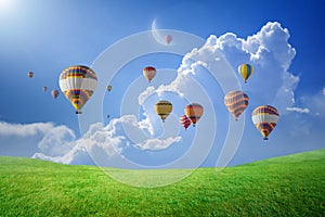 Hot air balloons flying in blue sky above green field