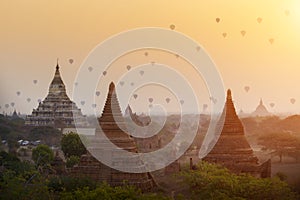 Hot air balloons flying over ancient pagodas with beautiful sunrise sky at Bagan, Myanmar. Asia travel destination.