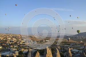 Hot air balloons flying over the valley and rock formations with fairy chimneys near Goreme, Cappadocia, Turkey