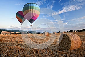 Hot air balloons over hay bales sunset landscape