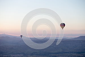 Hot air balloons over mountain landscape in Cappadocia, Goreme National Park, Turkey.