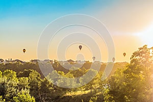 Hot air balloons over the roofs of suburban houses in the light of the low evening sun backlight