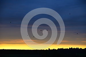 Hot air balloons over woods on the sunset sky background