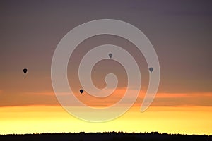 Hot air balloons over woods on the sunset sky background