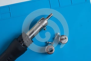 Hot air gun for soldering, and its attachments on the background of a blue mat