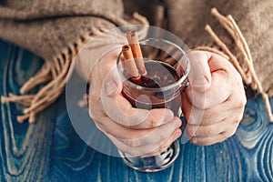 Hot alcohol drink, mulled wine with spices in male hand