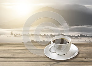 Hot americano black coffee in white mug with sunrise mountain photo
