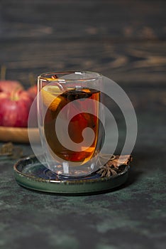 Hot apple honey punch or cider on dark green background. Traditional fall or winter warming spicy beverage with cinnamon