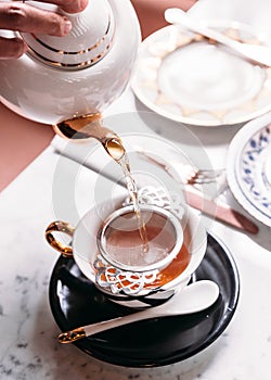 Hot Apple Tea served by pouring from mug through stainless steel tea strainer infuser in porcelain vintage cup