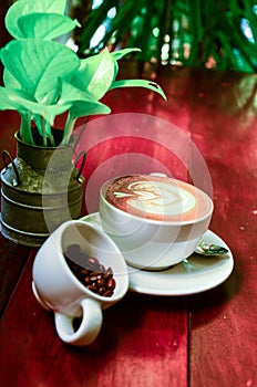 Hot art cappuccino Coffee and coffee beans in cup on wooden table