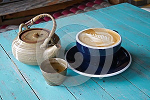 Hot art Latte Coffee and tea in a cup on blue wooden table.