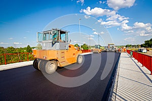 Hot asphalt is spreading with steamroller during road works