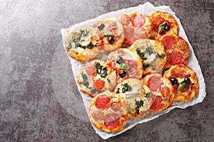 Hot assorted mini pizza or Pizzette with various toppings close-up on parchment. horizontal top view photo