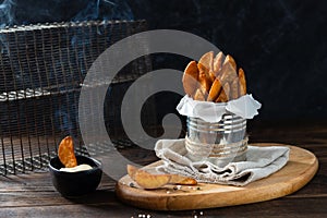 Hot Baked potato wedges with addition sea salt and pepper with sauce on a black background, side view, copy space