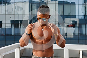 Hot Beautiful black guy with bulging muscles posing against the backdrop of the urban landscape. Man fitness model.