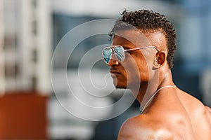 Hot Beautiful black guy with bulging muscles posing against the backdrop of the urban landscape. Man fitness model beautiful man.