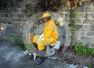 A hot beekeeper sitting in the shade with his smoker after working with his hives in the tropics