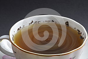 Hot beverage. Cup of tea with tea leaves in it. Ceramics. Close-up view