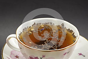 Hot beverage. Cup of tea with tea leaves in it. Ceramics. Close-up view