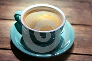 Hot black coffee in blue ceramic cup on wooden table background. photo